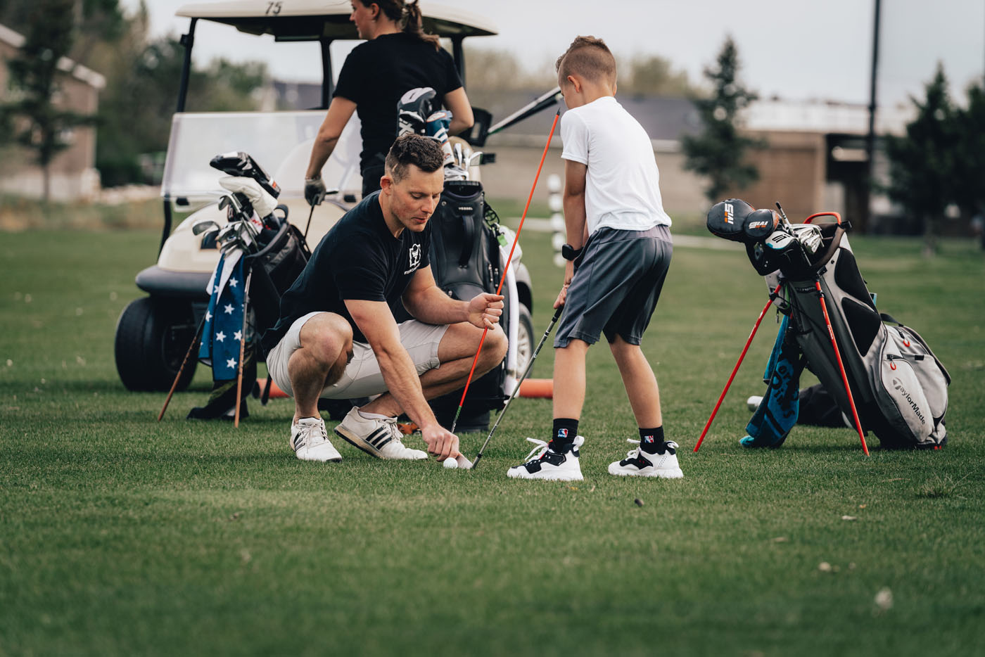 A Tee Box employee working with a group of kids on a golf course in Centerville, UT.
